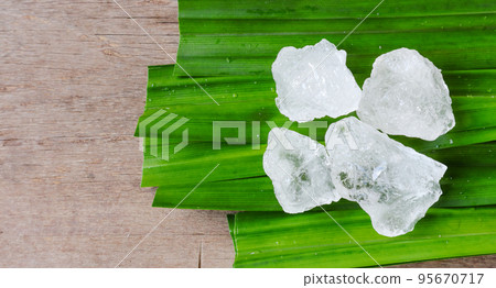 Crystal clear alum cubes or Potassium alum on green leaf Chemical compound substance Concept for beauty spa and underarm treatment industrial Crystal clear alum cubes or Potassium alum on green leaf Chemical compound substance Concept for beauty spa and underarm treatment industrial 95670717