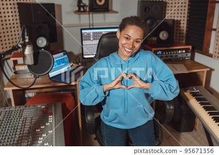 Pretty woman, sound engineer gestures, showing a heart shape from fingers the sound recording or broadcasting studio 95671356