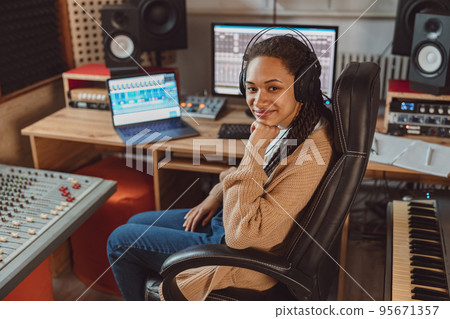 Pretty young multiethnic woman, musician, composer, sound engineer at work in recording studio, smiles looking at camera 95671357
