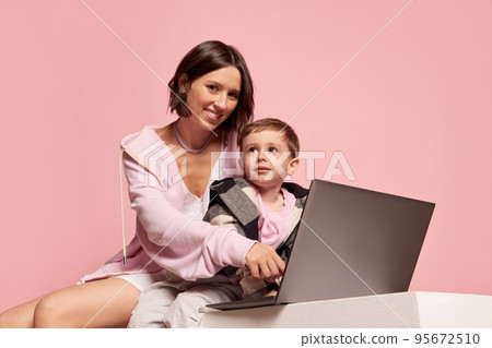 Cheerful young woman and little boy, mother and son using laptop isolated on pink studio background. Mother's Day celebration. Concept of family, childhood, motherhood Cheerful young woman and little boy, mother and son using laptop isolated on pink studio background. Mother's Day celebration. Concept of family, childhood, motherhood 95672510