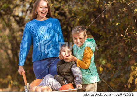 Mother have fun time with kids, use garden wheelbarrow 95672521