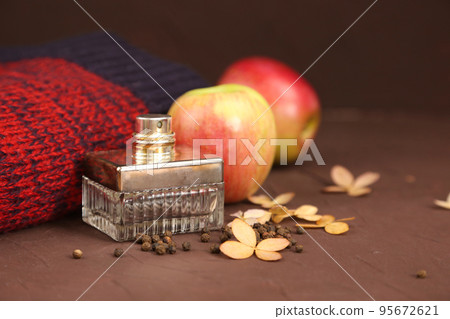 Perfume vintage square spray bottle, red apples, dry hydrangea and Christmas or autumn red knitted sweater on brown background. Mockup with copy space. Bottle for branding and label, front view. Perfume vintage square spray bottle, red apples, dry hydrangea and Christmas or autumn red knitted sweater on brown background. Mockup with copy space. Bottle for branding and label, front view. 95672621