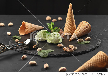 Gourmet chocolate and pistachio ice cream served on a stone slate over a black background. 95672927