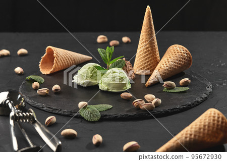 Gourmet chocolate and pistachio ice cream served on a stone slate over a black background. 95672930