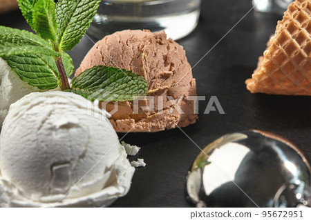 Gourmet creamy and chocolate ice cream served on a stone slate over a black background. 95672951