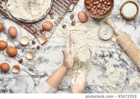 Close-up shot. Top view of a baker cook place, hands are working with a raw dough on the marble table background. 95672958