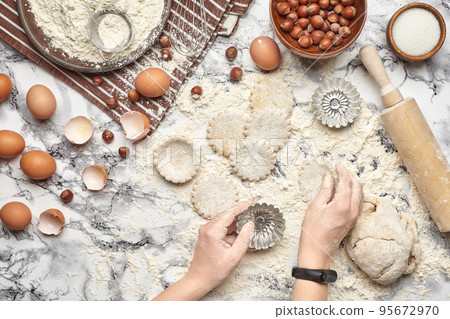 Close-up shot. Top view of a baker cook place, hands are working with a raw dough on the marble table background. Close-up shot. Top view of a baker cook place, hands are working with a raw dough on the marble table background. 95672970