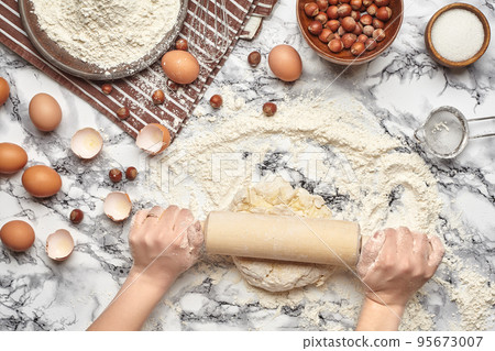 Close-up shot. Top view of a baker cook place, hands are working with a raw dough on the marble table background. Close-up shot. Top view of a baker cook place, hands are working with a raw dough on the marble table background. 95673007