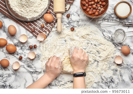 Close-up shot. Top view of a baker cook place, hands are working with a raw dough on the marble table background. Close-up shot. Top view of a baker cook place, hands are working with a raw dough on the marble table background. 95673011