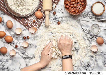 Close-up shot. Top view of a baker cook place, hands are working with a raw dough on the marble table background. Close-up shot. Top view of a baker cook place, hands are working with a raw dough on the marble table background. 95673012