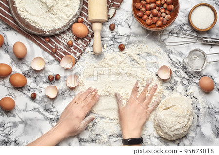 Close-up shot. Top view of a baker cook place, hands are working with a raw dough on the marble table background. 95673018