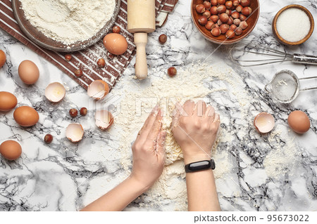 Close-up shot. Top view of a baker cook place, hands are working with a raw dough on the marble table background. Close-up shot. Top view of a baker cook place, hands are working with a raw dough on the marble table background. 95673022