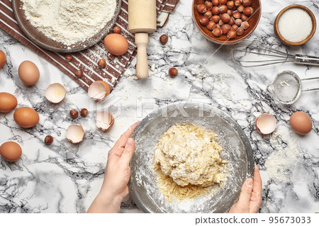 Close-up shot. Top view of a baker cook place, hands are working with a raw dough on the marble table background. 95673033