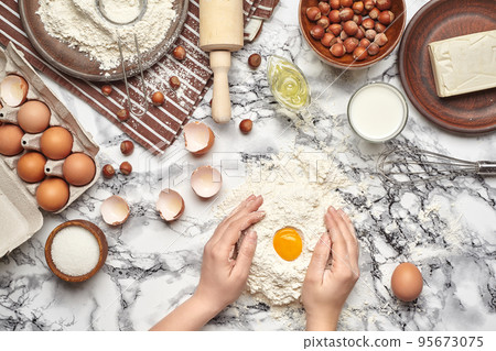 Close-up shot. Top view of a baker cook place, hands are working with a raw dough on the marble table background. 95673075