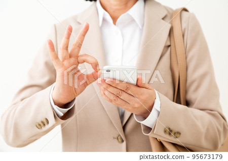 Middle female business woman holding a smartphone and making a circle sign 95673179
