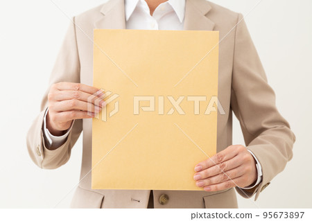 Middle female businesswoman holding an envelope with documents Middle female businesswoman holding an envelope with documents 95673897