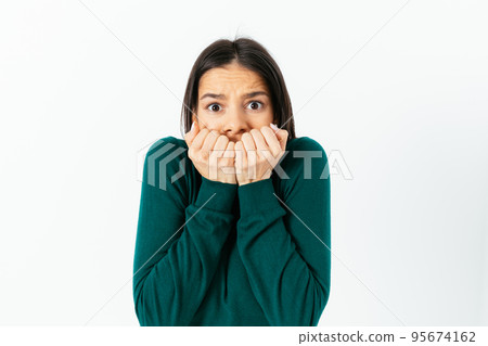 Frightened young woman biting her nails Frightened young woman biting her nails 95674162