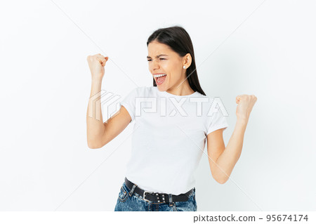 Jubilant young brunette woman celebrating victory holding Jubilant young brunette woman celebrating victory holding 95674174