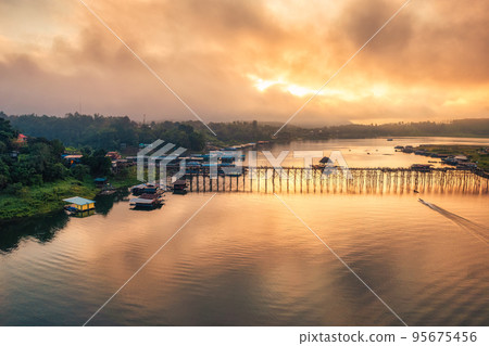 Golden sunrise over Mon wooden bridge on Songkalia river and Mon local village at Sangkhlaburi Golden sunrise over Mon wooden bridge on Songkalia river and Mon local village at Sangkhlaburi 95675456