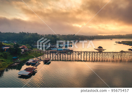 Golden sunrise over Mon wooden bridge on Songkalia river and Mon local village at Sangkhlaburi 95675457