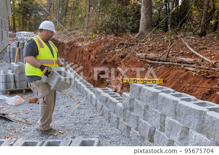 Contractor is induring the installation process of installing large block retaining wall constructed on construction site 95675704