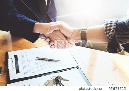 Focus on the congratulatory handshake. The real estate agent agrees to buy the home and hand the keys to the customer at the agent's office. conceptual agreement 95675725