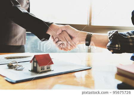 Focus on the congratulatory handshake. The real estate agent agrees to buy the home the customer at the agent's office. concept agreement 95675726