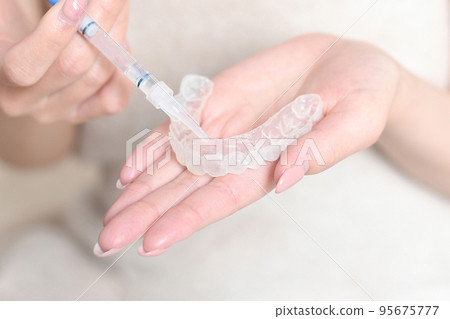 Image of applying gel to home whitening mouthpiece 95675777