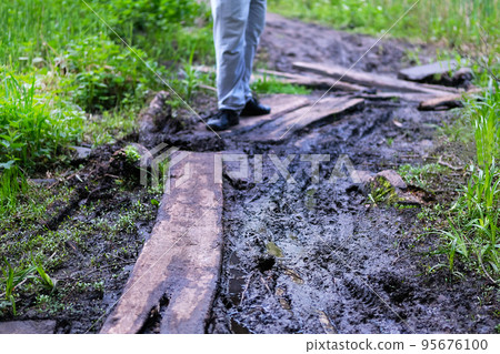 Road grooves filled with water and mud. Off road trails. Man walk along the forest trail. Road grooves filled with water and mud. Off road trails. Man walk along the forest trail. 95676100