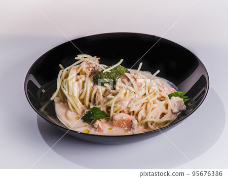 Salmon pasta, tagliatelle with fish and creamy sauce. Italian dinner with seafood. White background, top view Salmon pasta, tagliatelle with fish and creamy sauce. Italian dinner with seafood. White background, top view 95676386