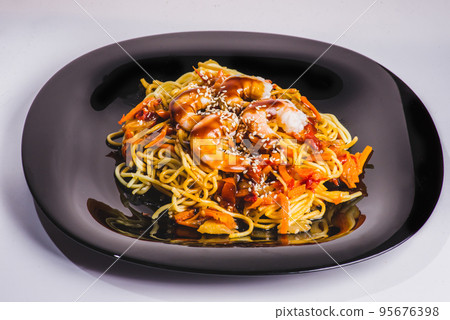 A bowl of delicious spicy asian shrimp noodle soup with mushroom, red pepper, snow peas and scallions. 95676398