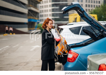 A woman puts things in the car A woman puts things in the car 95676537
