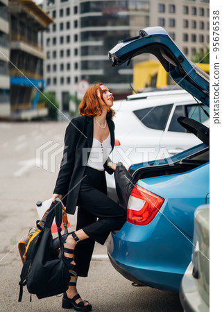 A woman puts things in the car A woman puts things in the car 95676538