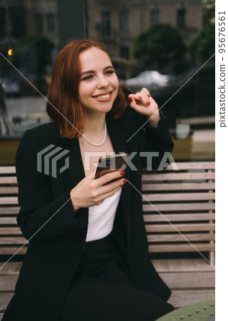 Young woman uses the phone at the street cafe Young woman uses the phone at the street cafe 95676561
