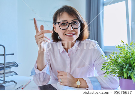 Webcam view of talking mature woman sitting at desk in home office Webcam view of talking mature woman sitting at desk in home office 95676657