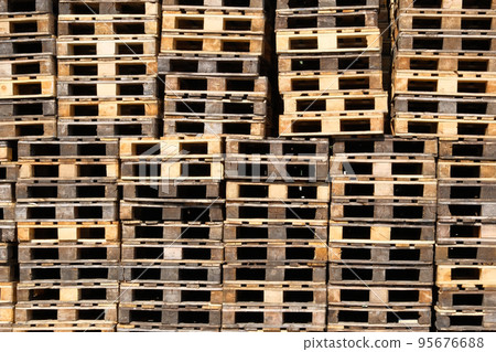 Pallets background. Stacks of rough wooden pallets at warehouse in industrial yard. Cargo and shipping concept. Pallets background. Stacks of rough wooden pallets at warehouse in industrial yard. Cargo and shipping concept. 95676688