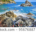 Panoramic photo of the rocky seashore with the feet of tourists in sandals, women and men. The concept of hiking ordinary people along the coast. 95676887