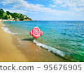 Panoramic photo of a man carrying an inflatable pink flamingo on a sandy beach along the sea. For registration of tourist holidays, vacations, sea holidays. 95676905