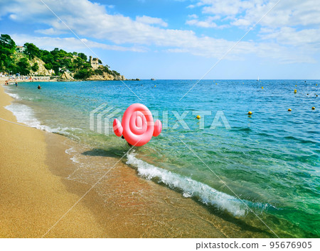Panoramic photo of a man carrying an inflatable pink flamingo on a sandy beach along the sea. For registration of tourist holidays, vacations, sea holidays. Panoramic photo of a man carrying an inflatable pink flamingo on a sandy beach along the sea. For registration of tourist holidays, vacations, sea holidays. 95676905