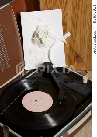 Vintage vinyl record player. Homemade greeting card in white. With decorative elements. Ribbons, flowers and leaves are attached to cardboard. Vintage vinyl record player. Homemade greeting card in white. With decorative elements. Ribbons, flowers and leaves are attached to cardboard. 95676911
