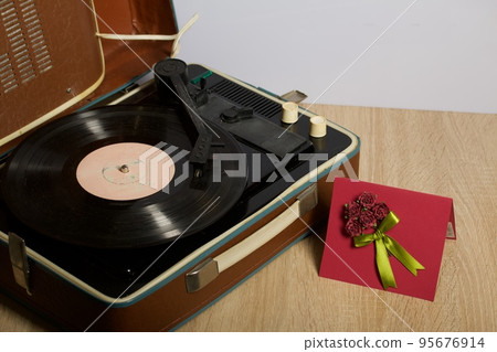 Vintage vinyl record player. Homemade greeting card. With decorative elements. Ribbons, flowers and leaves are attached to cardboard. 95676914