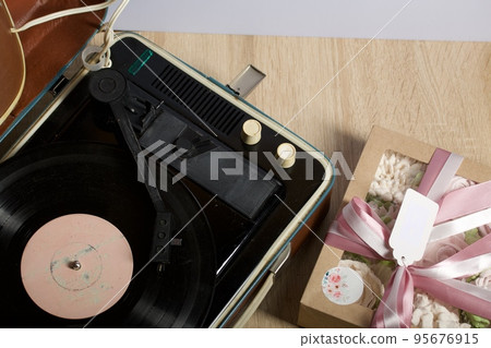 Vintage vinyl record player. The vinyl record is spinning. Homemade marshmallows in a gift box. Tied with ribbon. Zephyr flowers. 95676915