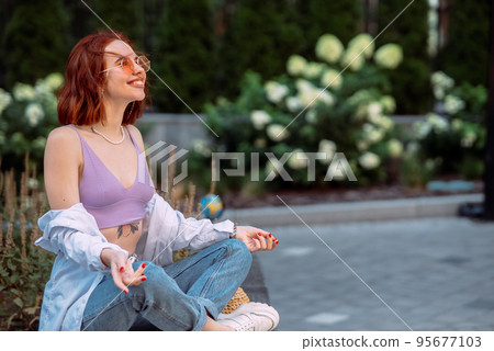 Young red-haired woman sitting in lotus position Young red-haired woman sitting in lotus position 95677103