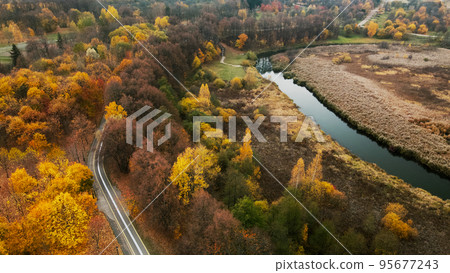 Autumn city park. Trees with colorful leaves. A cycle path winds between the trees. Autumn landscape. Aerial photography. 95677243
