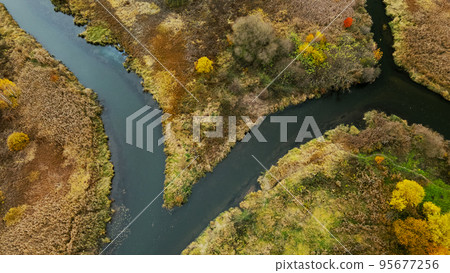 Autumn city park. A meandering river flows between the trees. Trees with colorful leaves. Autumn landscape. Aerial photography. Autumn city park. A meandering river flows between the trees. Trees with colorful leaves. Autumn landscape. Aerial photography. 95677256
