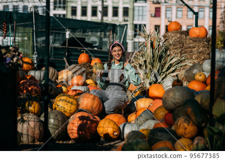 Female farmer holding ripe pumpkin and showing thumb up. Female farmer holding ripe pumpkin and showing thumb up. 95677385