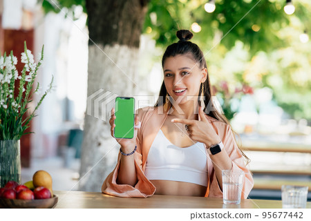 Woman hold smartphone and point at phone. 95677442