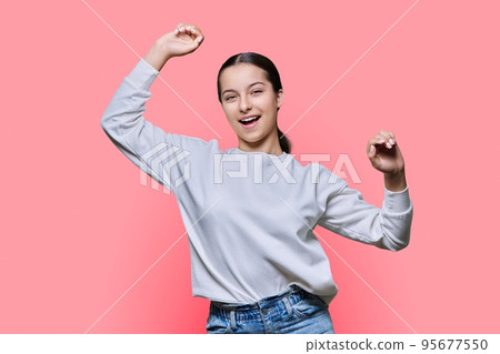 Cheerful dancing teenage girl on pink studio background 95677550