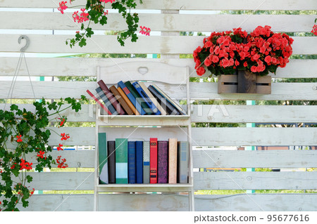 Book stack of step to success concept, flowering plants in pots on background. Vintage books with empty labels with free copy space on a white shelf. 95677616