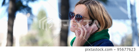 Smiling woman talking on phone in street Smiling woman talking on phone in street 95677623